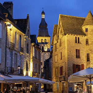 France, Nouvelle-Aquitaine, Dordogne, Perigord, Sarlat-la-Caneda, Tower of the Cathedrale Saint-Sacerdos and old houses on the Place de la Liberte, illuminated at night