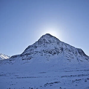 Glen Coe, Scotland. The sun hides behind Meall Mor in snow covered Glen Coe