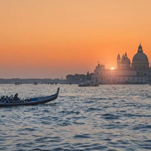 Gondola on the Grand Canal at sunset with Basilica of Saint Mary of Health in background