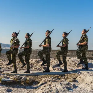 Greek army soldiers perform a ceremonial march on the Acropolis before raising the