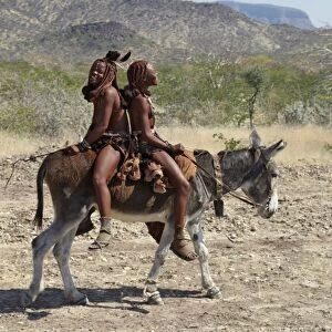 Two happy Himba girls ride a donkey to market