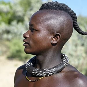 A Himba youth with his hair styled in a long plait, known as ondatu