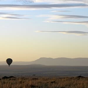 A hot air balloon floating over the Masai Mara Game Reserve at daybreak