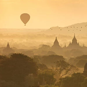 Hot air balloons fly over the temples of Bagan at sunrise on a misty morning, Myanmar