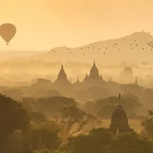 Hot air balloons fly over the temples of Bagan at sunrise on a misty morning, Myanmar Hot air balloons fly over the temples of Bagan at sunrise on a misty morning, Myanmar