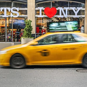 I Love New York gift shop sign and blurred yellow taxi cab passing, Times Square
