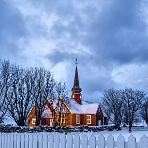The illuminated church at dusk in the cold snowy landscape at Flakstad Lofoten Norway