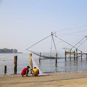 India, Kerala, Cochin - Kochi, Fishermen untable thir nets inthe background are Chinese
