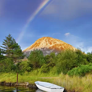 Ireland, Co. Donegal, Boat in lake infront of Mount Errigal with rainbow