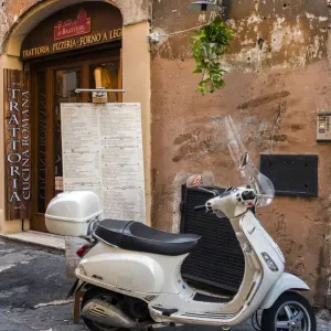 La escotilla de Vespa italiana estacionada fuera una trattoria restaurante en una calle empedrada La escotilla de Vespa italiana estacionada fuera una trattoria restaurante en una calle empedrada