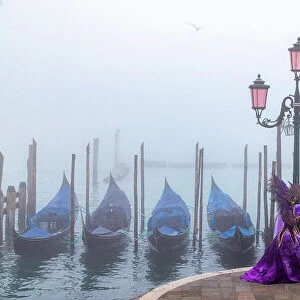 Italy, Veneto, Venice, a couple pose in costume during the Venice Carnival on a foggy day