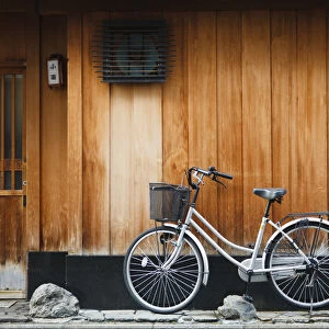 Japan, Chubu Region, Kyoto, Gion. A bicycle rests against the wall of a traditional
