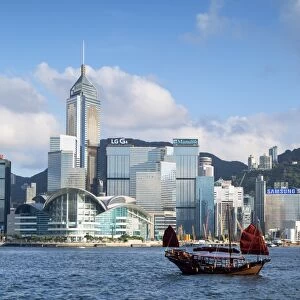 Junk boat passing Convention Centre and Hong Kong Island skyline, Hong Kong, China