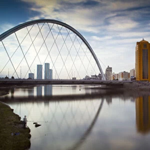 Kazakhstan, Astana, Man fishing by Bridge reflecting in Ishim River
