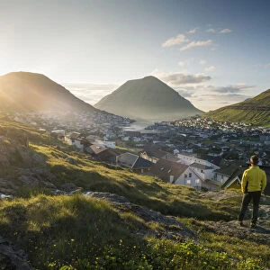 Klaksvik, Bordoy island, Faroe Islands, Denmark. Man watching the city at sunset. (MR)