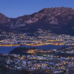 Lecco lights up at dusk from the Plain of San Tomaso, lake Como, Lombardy, Italy, Europe