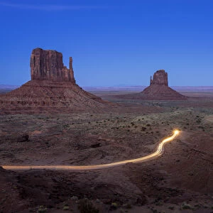 Light trail from car driving on scenic drive road near The Mitten Buttes in Monument