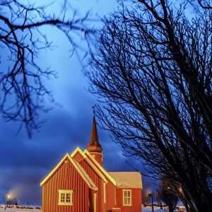 Lights on the church at dusk with the snowy peaks in the background Flakstad Lofoten