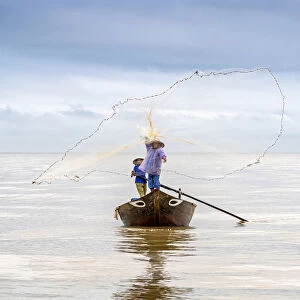 Local fisherman casting the fishing net from the boat, near Hoi An, Vietnam