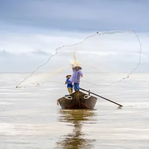 Local fisherman casting the fishing net from the boat, near Hoi An, Vietnam