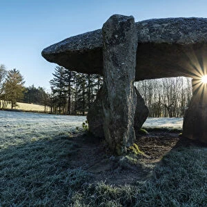 Low winter sun rising through the Neolithic dolmen Spinsters Rock near Drewsteignton in