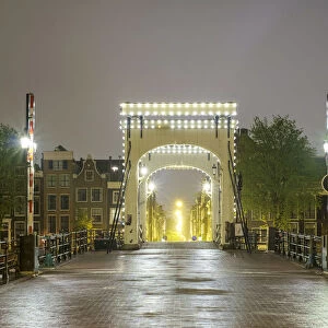 Magere Brug illuminated at night on foggy evening, Amsterdam, North Holland, Netherlands
