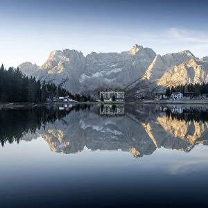 The majestic Sorapiss mountain and the small village of Misurina perfectly reflecting in the Misurina lake duirng a calm autumn morning. Dolomites, Italy