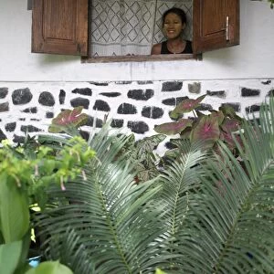 A Malagasy woman admires her garden from the window