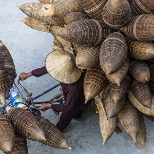 A man on the bicycle loaded with the conical bamboo fish traps, near Hanoi, Vietnam