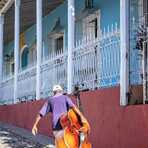 A man carrying a cello in Plaza Mayor in Trinidad, Sancti Spiritus, Cuba