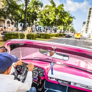 A man driving a classic car in Centro Habana District, Havana, Cuba A man driving a classic car in Centro Habana District, Havana, Cuba