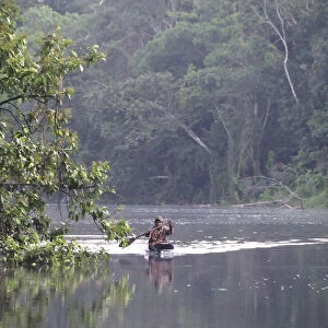 Man in a dugout canoe on the Amazon River, near Puerto Narino, Colombia