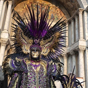 A man in an elaborate costume stands in front of the Basilica Saan Marco in St