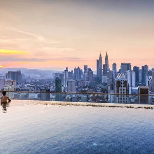 Man in a infinity pool overlooking Kuala Lumpur skyline, Malaysia