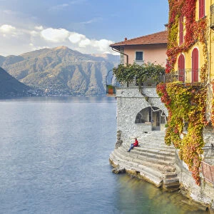 A man sitting on the steps of Nesso village admire the lake of Como, Como province