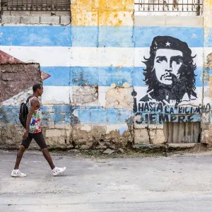 A man walking in a front of Che Guevara street art in La Habana Vieja (Old Town), Havana A man walking in a front of Che Guevara street art in La Habana Vieja (Old Town), Havana