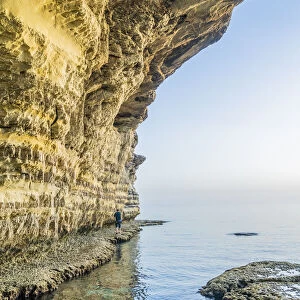 A man walking at the sea caves at Cape Greco, Famagusta District, Cyprus