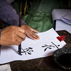 Man is writing with chinese idioms at Shigu Village or Stone Drum Village, Lijiang