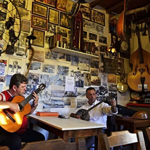 Men play musical instruments at a bar in Crete, Greece, Europe