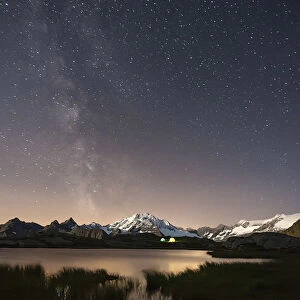 The Milky Way shines over the Fora Alp where some hikers have created their campsite