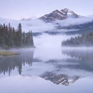 A misty Pyramid Mountain reflected in Pyramid Lake at dawn, Jasper National Park