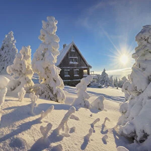 mountain cottage in deep snow-covered winter landscape at Fichtelberg at sunset