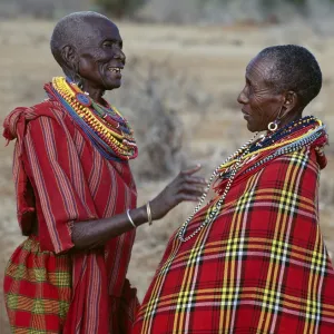 Two Msai women in traditional attire chat to each other