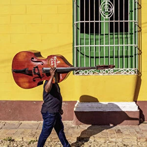 Musician with his double bass walking through the colourful street of Trinidad