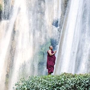 Myanmar, Mandalay division, Pyin Oo Lwin. Burmese monk praying under Dattawgyaik Waterfall