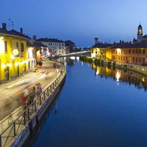 Naviglio Grande canal flows between the houses at dusk in Gaggiano, Milan, Italy