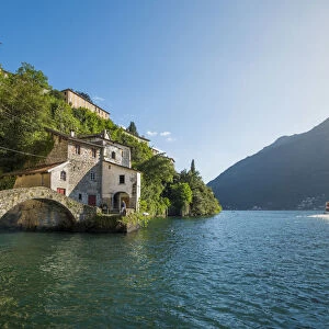 Nesso, lake Como, Como province, Italy. The roman stone bridge and a tourist boat