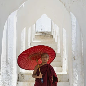 Novice monk with an umbrella standing at staircase hallway at Hsinbyume pagoda, Mingun