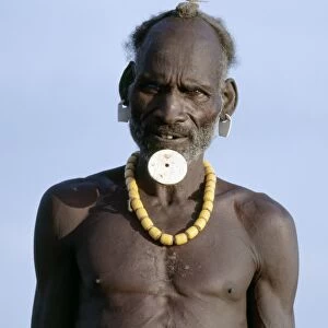 An old Dassanech man wearing a traditional lip ornament and earrings