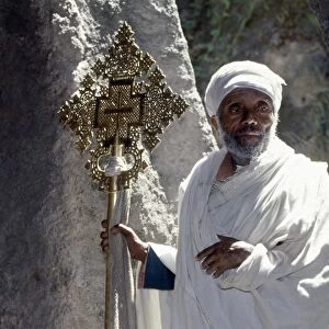 An old Ethiopian Orthodox priest holds a large brass
